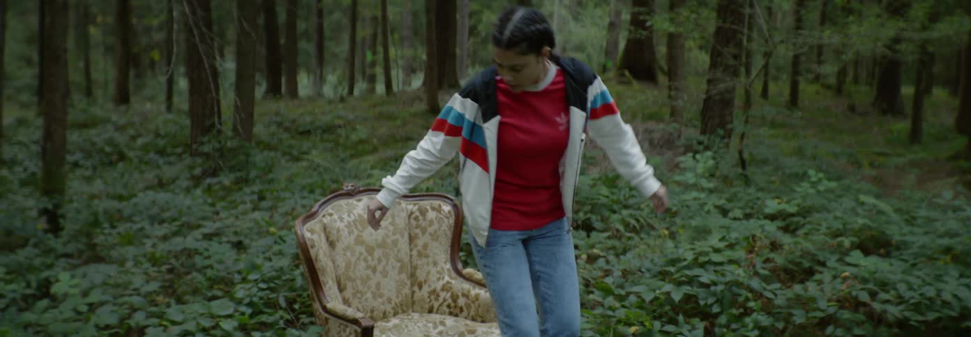 Girl stumbles backwards in the woods and falls into a chair
