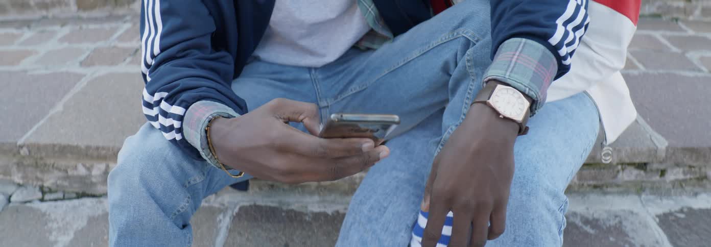 The man is sitting on the steps using his phone