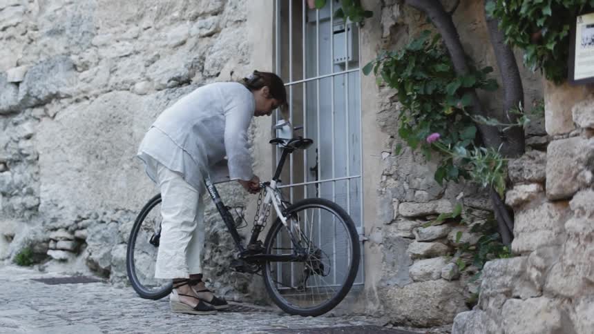 A woman lockups up her bicycle to a gate