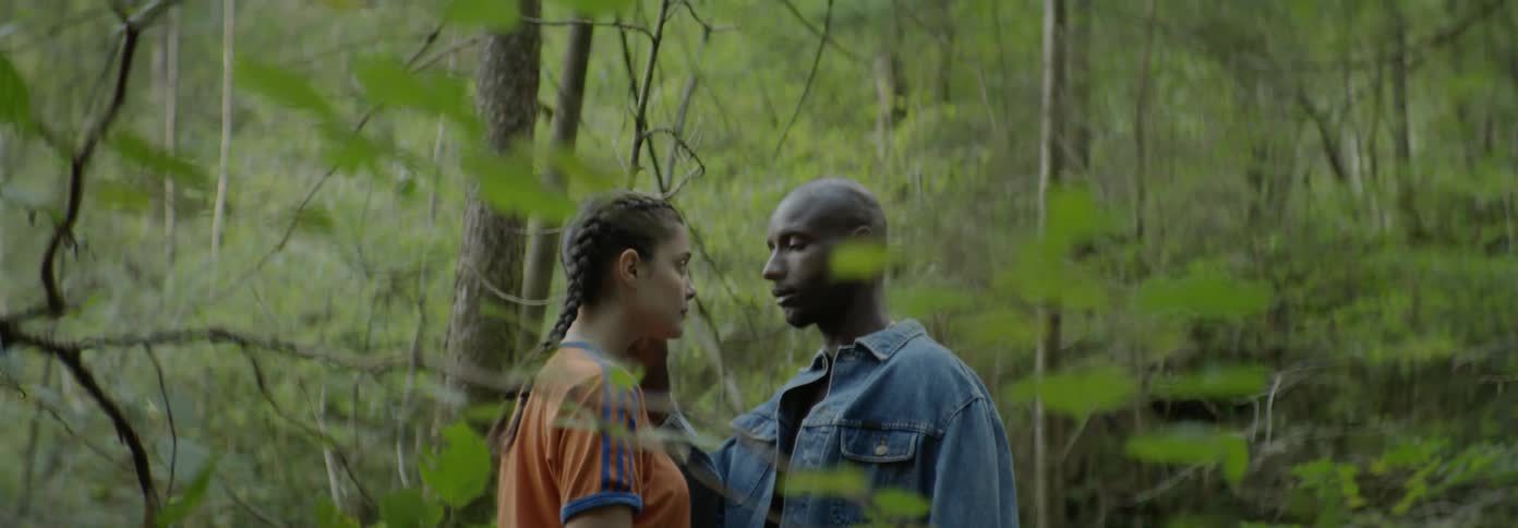 A man touches a woman's face in the woods