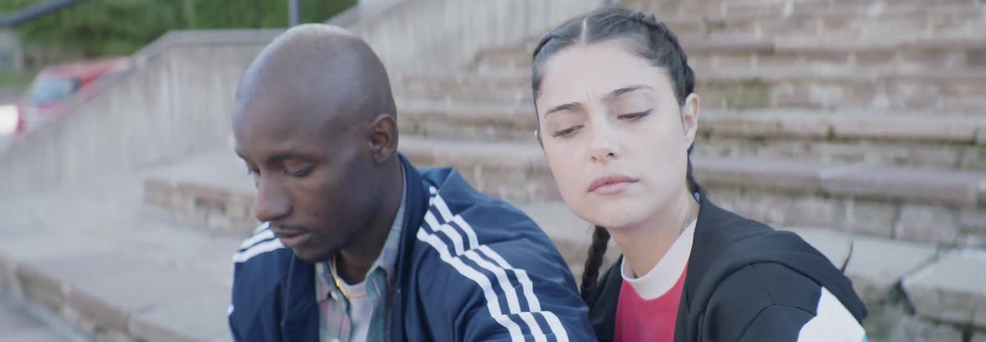 A woman puts her head on a man's shoulder