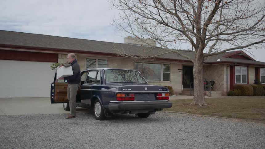 A man gets out of his car carrying a small box