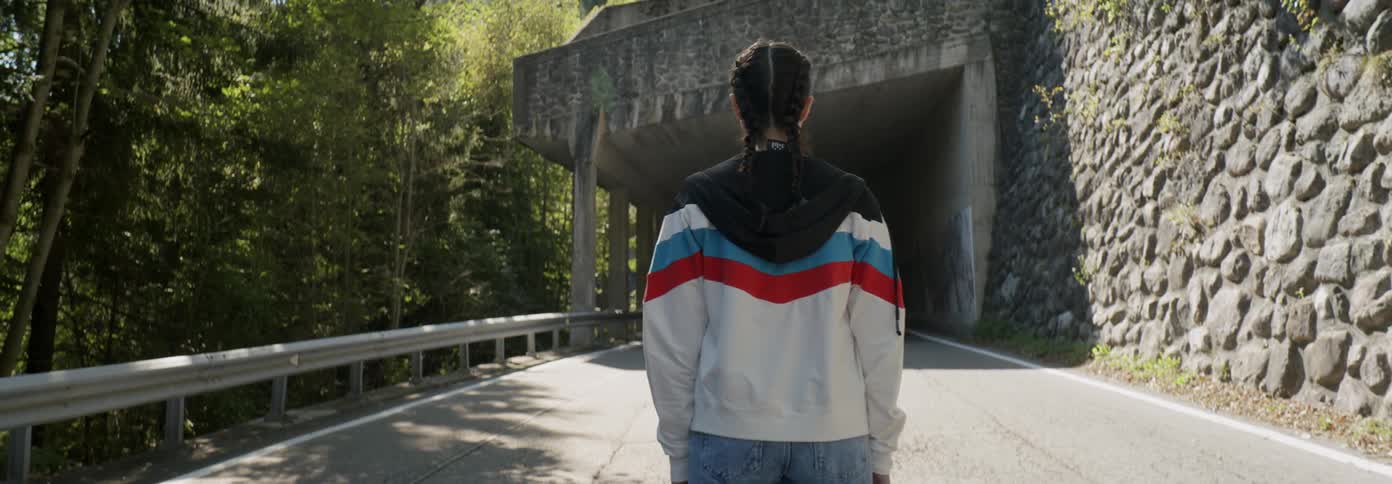 Woman wearing a jacket stands on a road looking at a tunnel