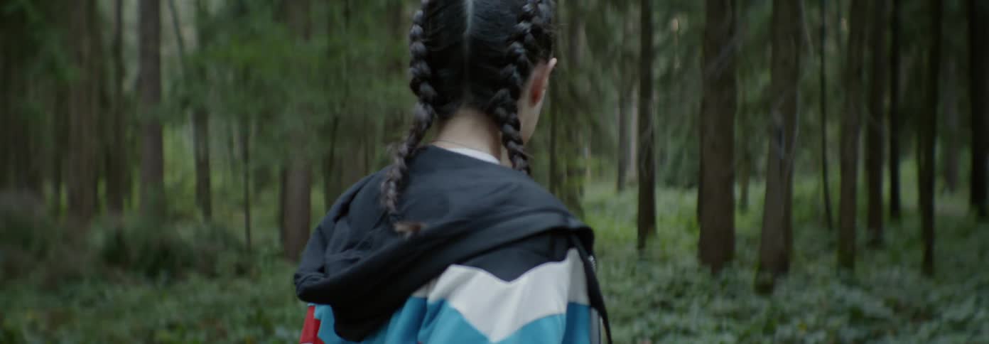 A woman looks around fast in the woods