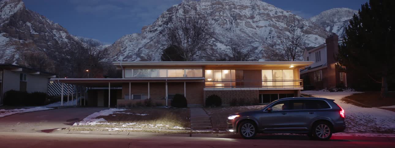 An suv parks in front of a house at night