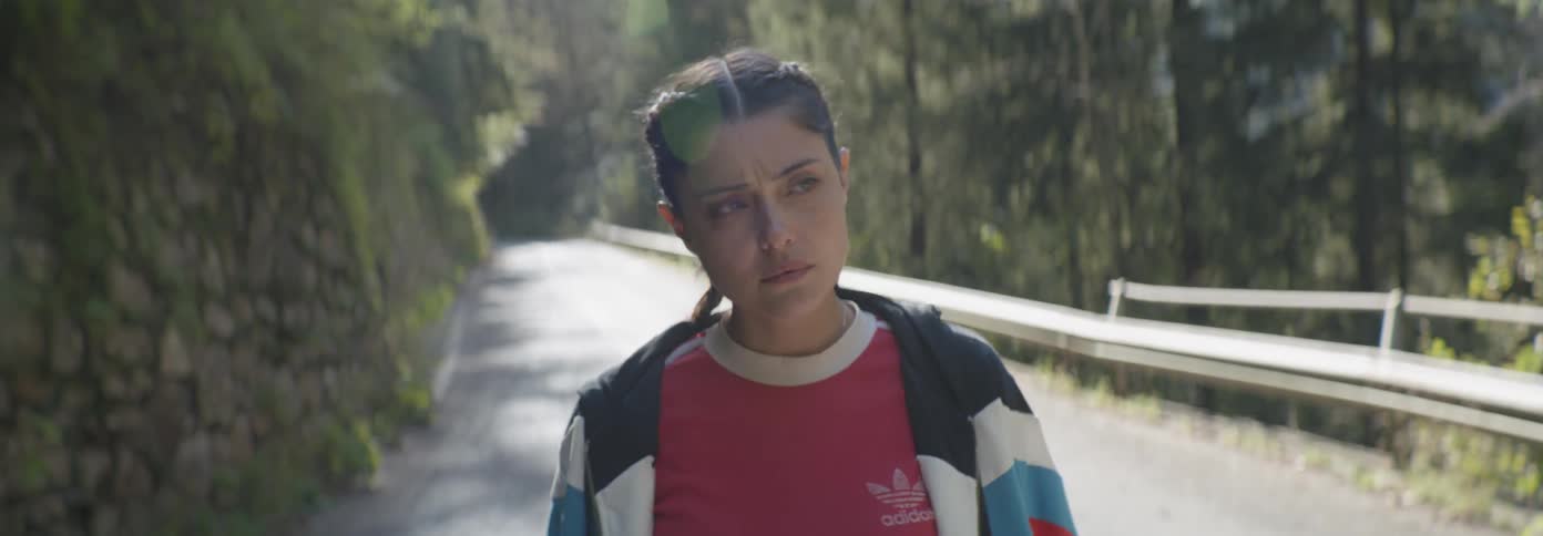 Woman walks on a sunny road in the middle of nature