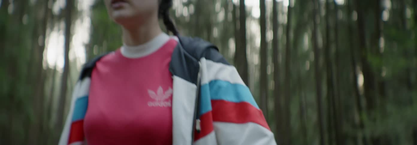 Woman looks around as she backs towards a forest