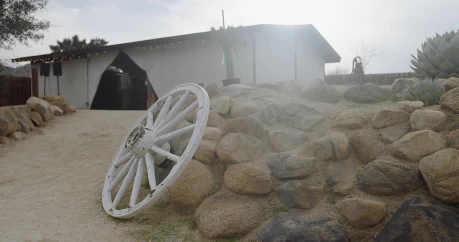 An old carriage wheel leans against the rocks