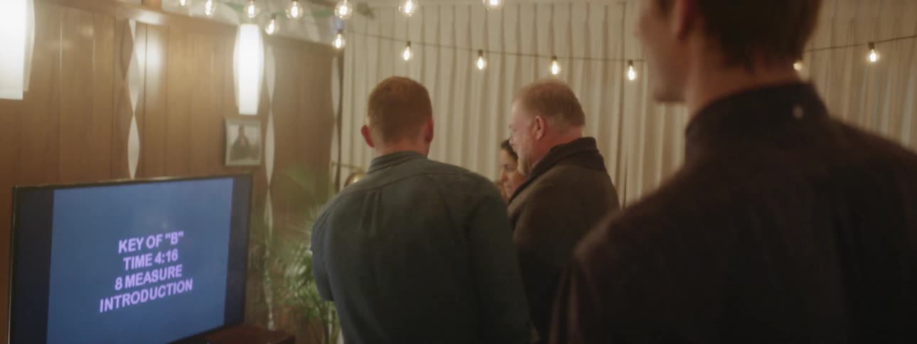 Group of people at a party watch karaoke instructions on a monitor