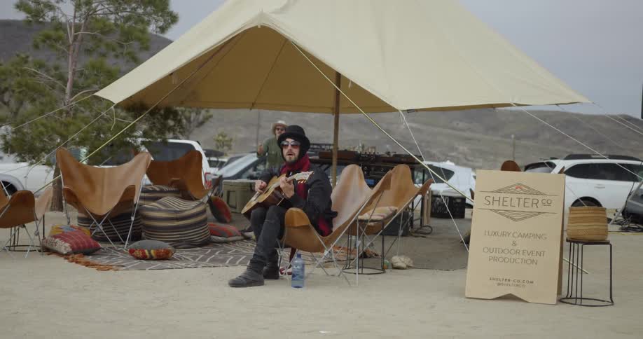 The man wearing a hat plays the guitar