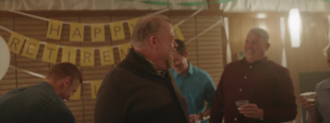 Man laughs as he talks to others standing around him at a party