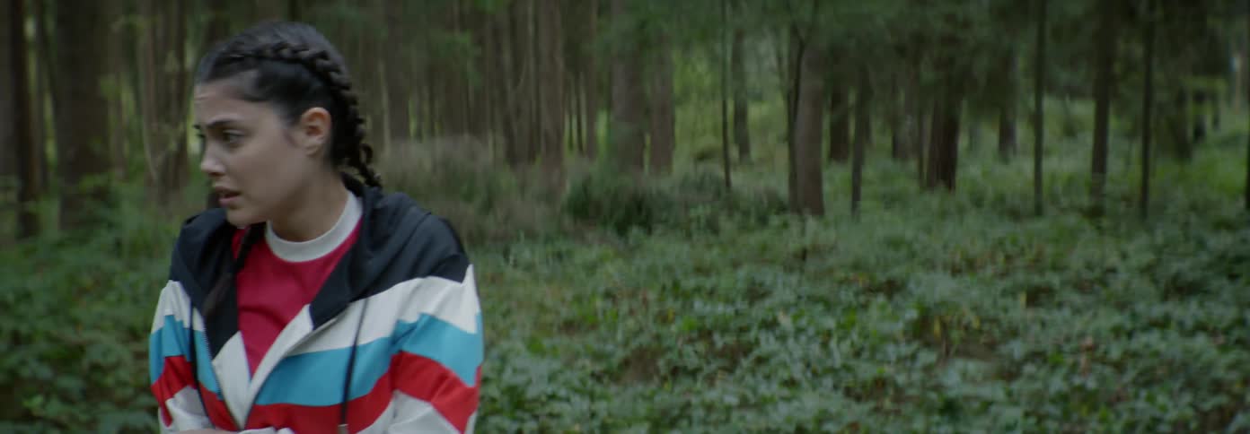 Woman in a striped jacket walks near the forest