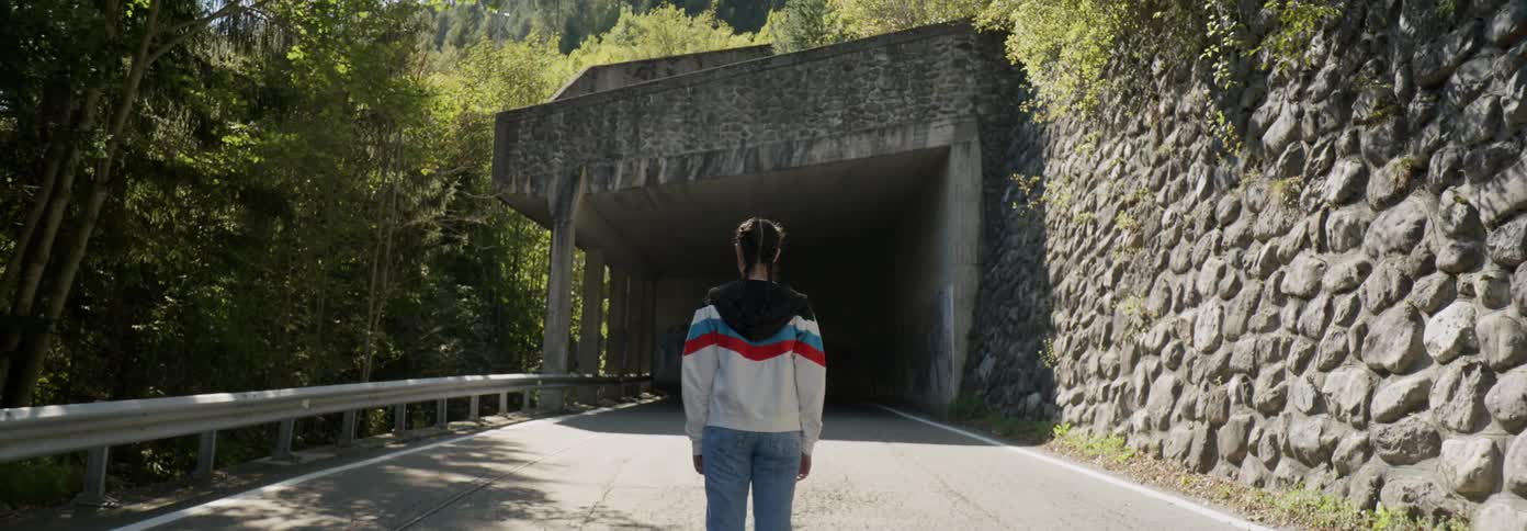 A woman stands before a tunnel on the road