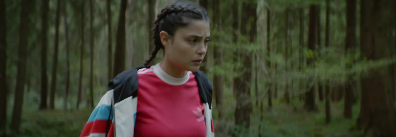 A woman walking backwards in the woods falls into a chair