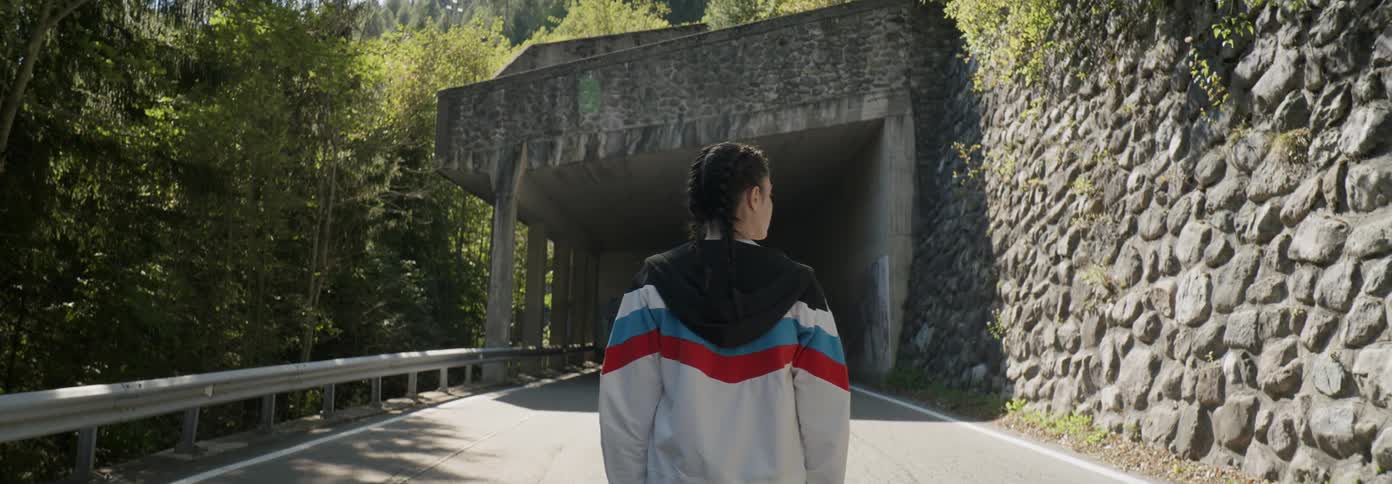 A woman stands on a mountain road by the tunnel