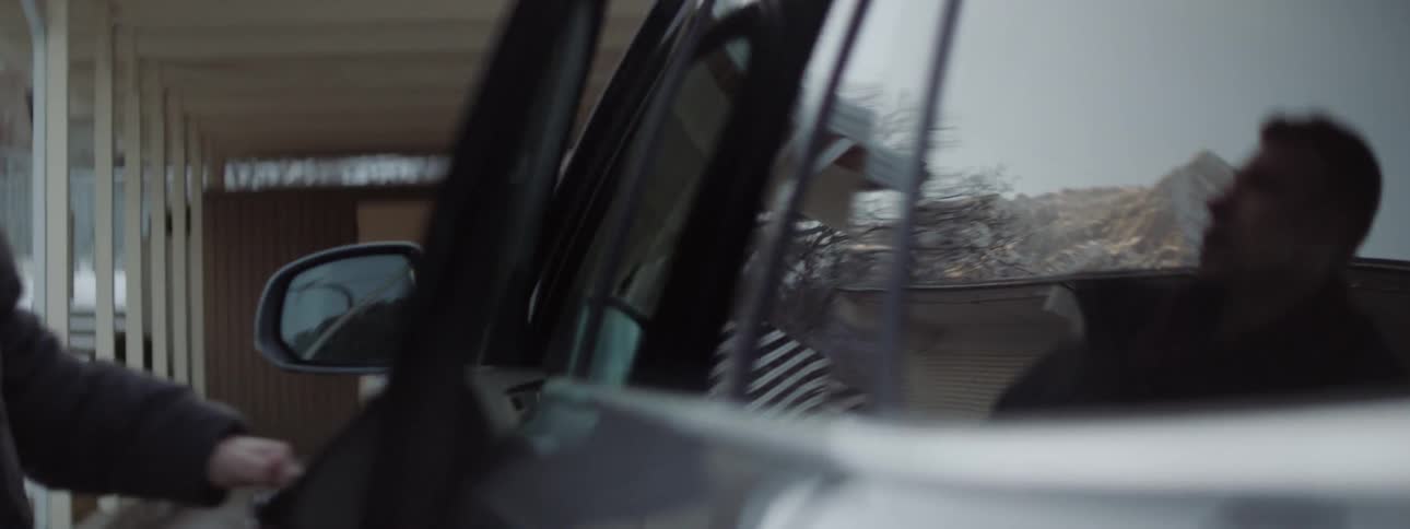 A man enters the driver seat of a car