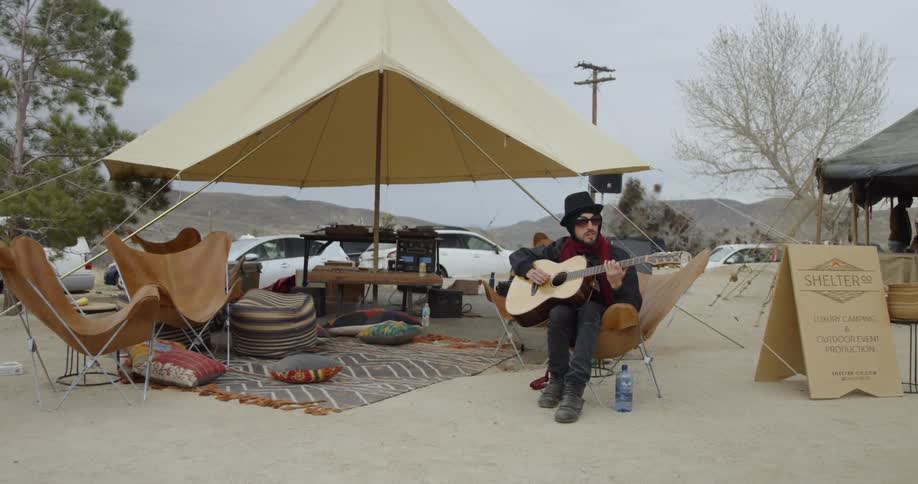 Man plays guitar next to a tent