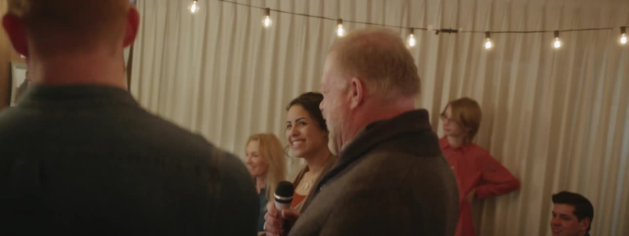 People are having fun at a party, and the man is holding a microphone