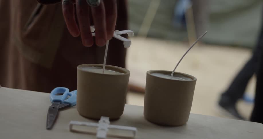A person lifts the guides off a candle wick