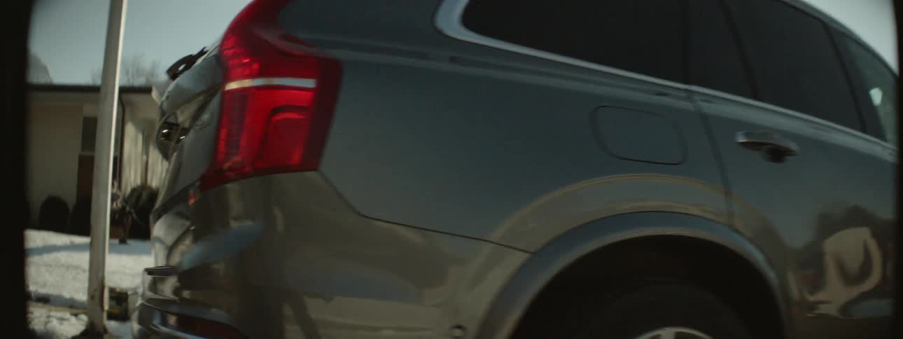 An suv is backing out of a driveway and pulling away on a winter day