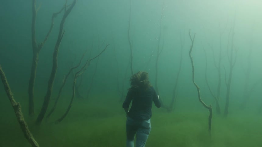 Woman runs under water near branches