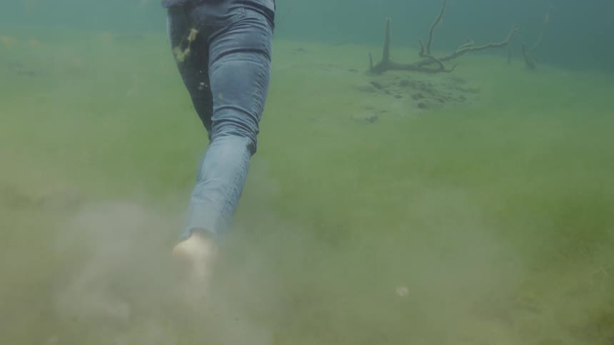Fully clothed woman walks underwater