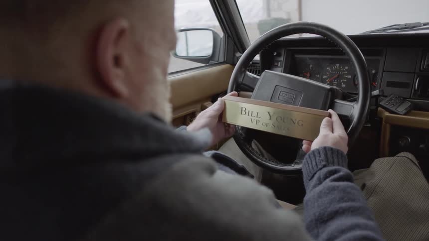 Man looks at a name plaque while sitting in a parked car