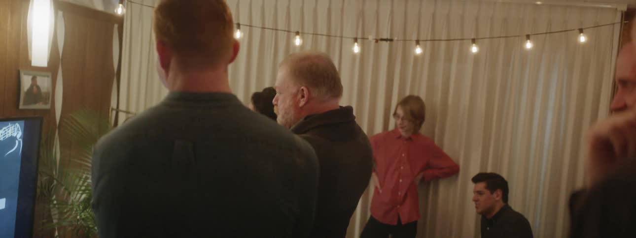 Man talks and laughs as he holds a microphone at a celebration