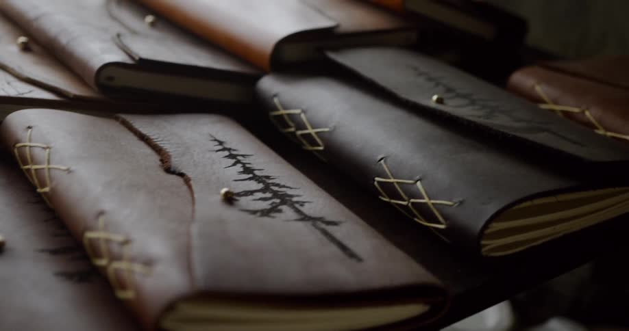Rows of leather bound notebooks lined up on a table