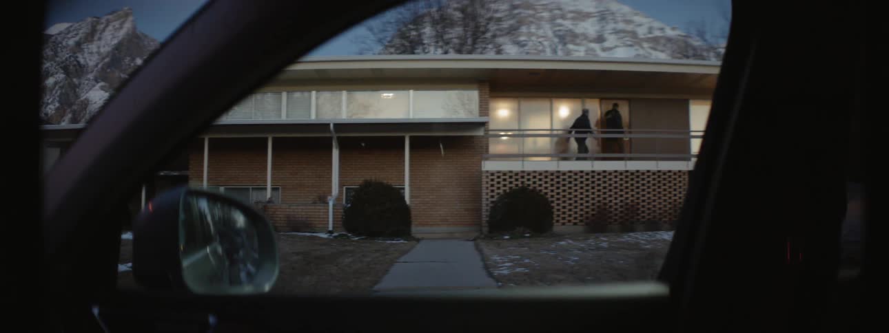 Two men walk up the front steps and enter a house