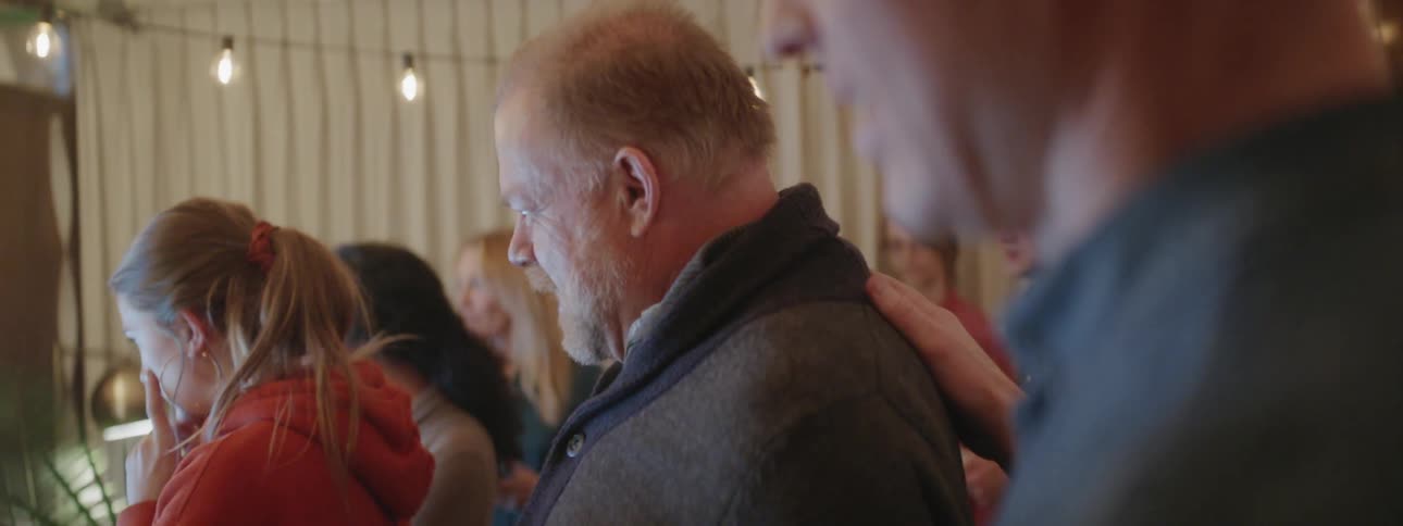 Man pats another man's shoulder in a crowd of people