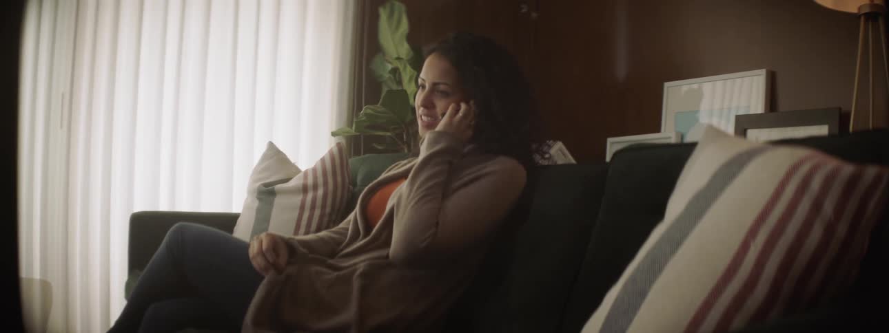 Woman talks on her cell phone as she sits on a sofa