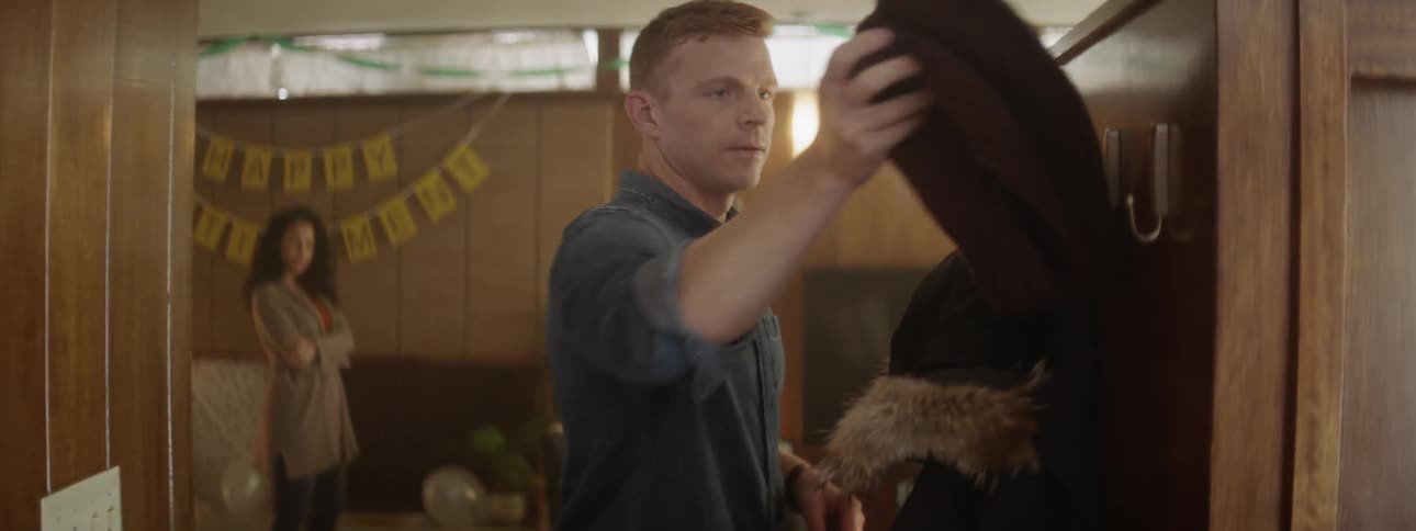 Man puts on a scarf and coat as a woman watches