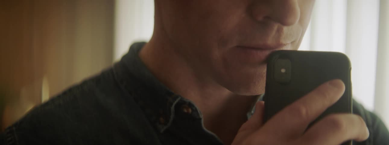 A man leans his phone against his face