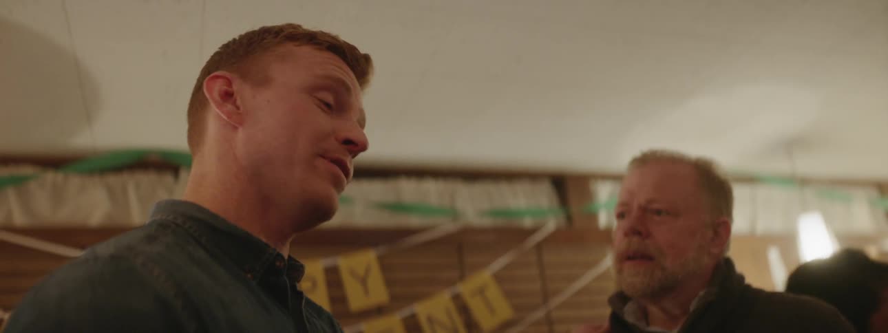 Two men talk as they stand in a party room