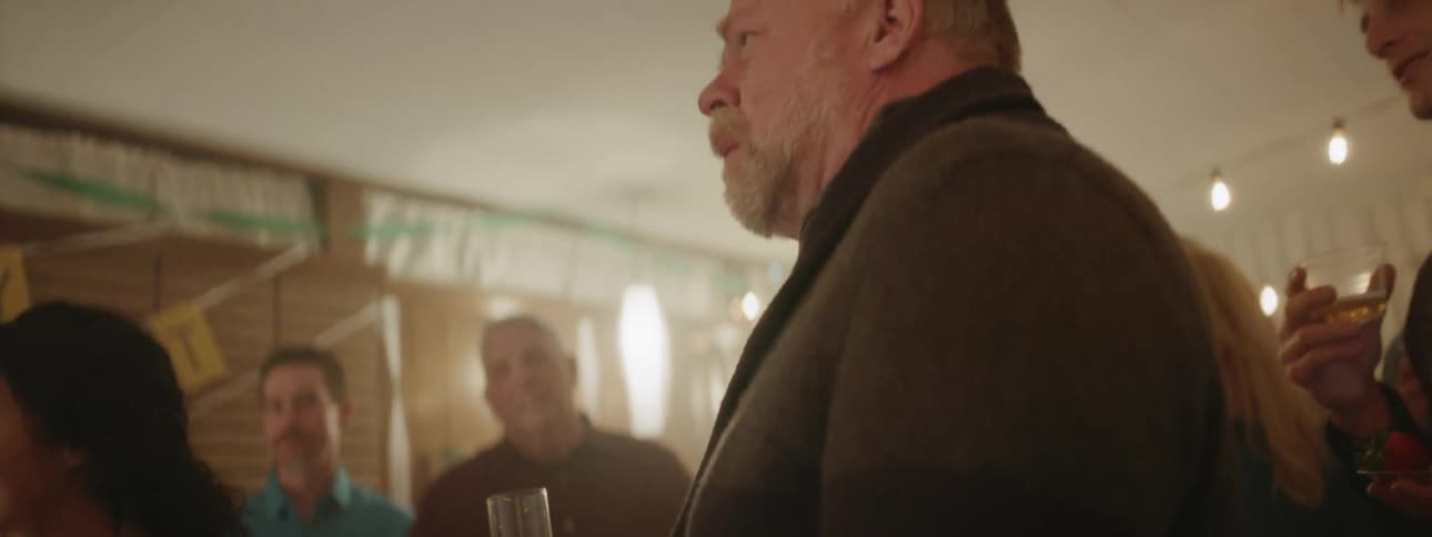 A man listens while another proposes a toast to him at a party