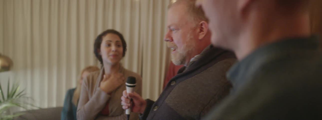 A man holds a microphone at a party