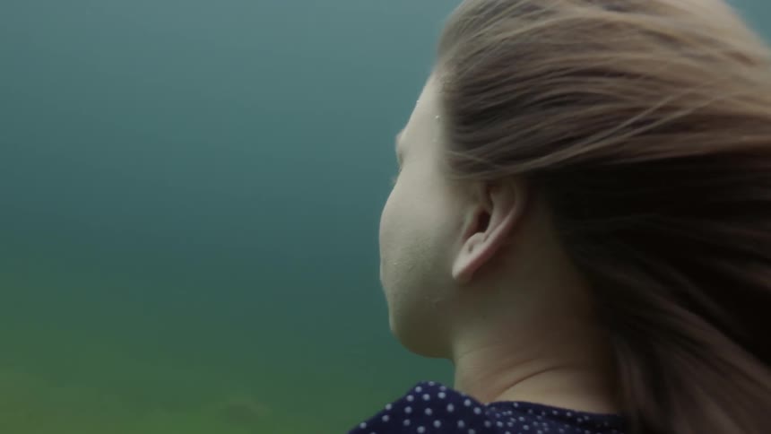 Woman floats underwater then pushes herself towards the surface