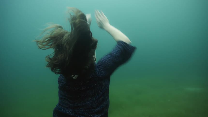 A woman slowly jumps from the bottom of the water up
