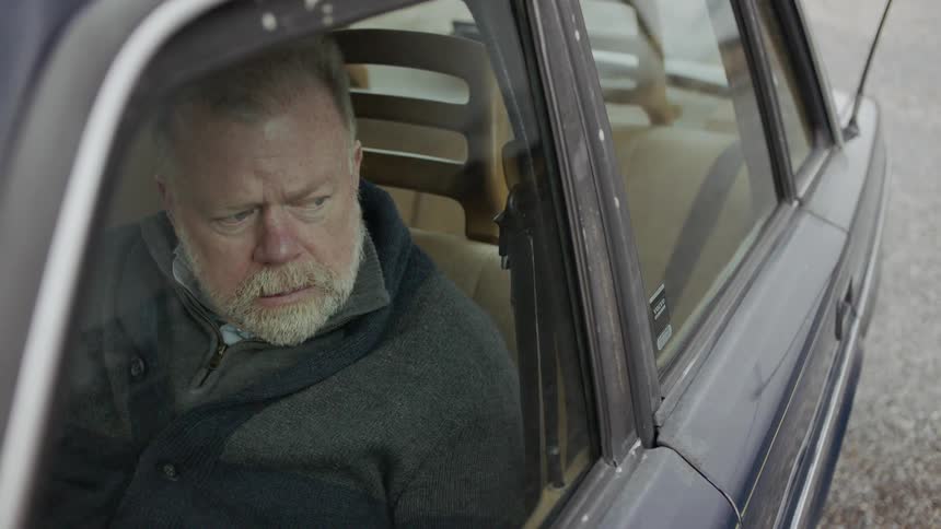 A man sits in his car looking out