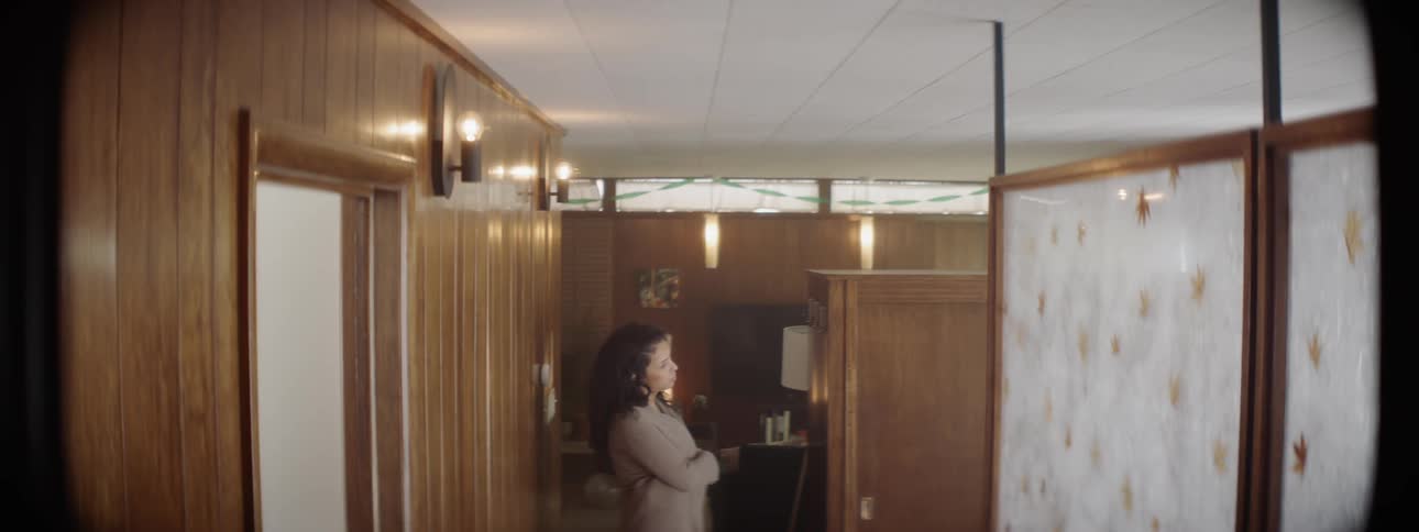 A woman stands down the hall with her arms folded