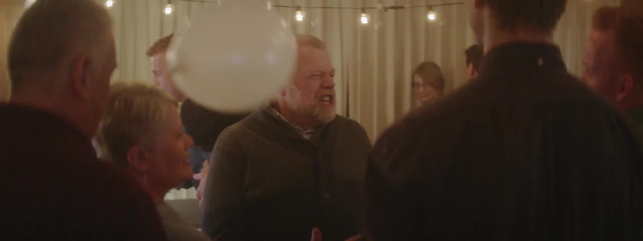 Group of people celebrate at a party as a man sings into a microphone
