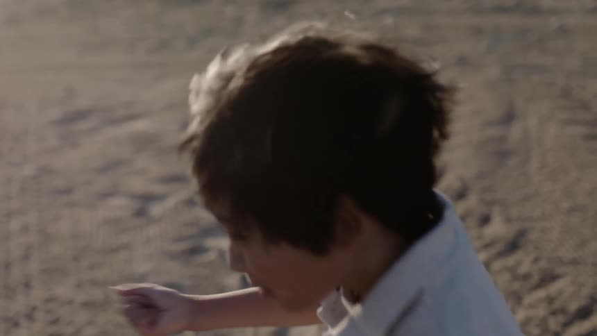 Child jumps and waves his arms outside on a sunny day