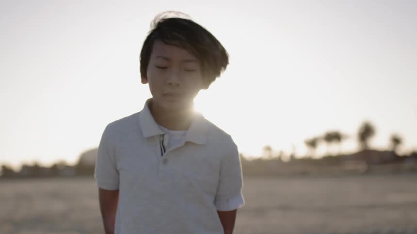 A boy runs on the sand at sunset