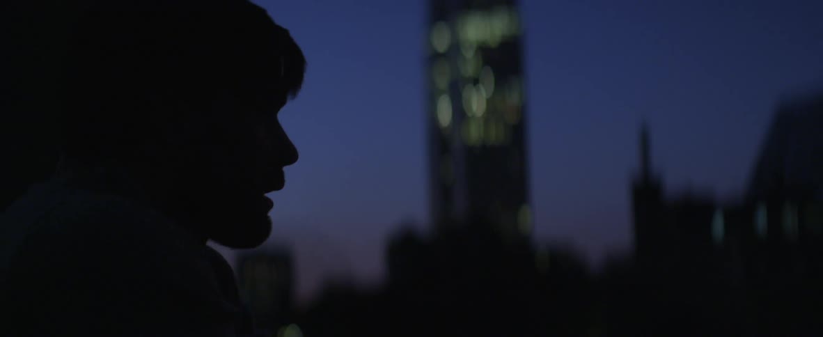 Man smoking a cigarette at night with a building in the background