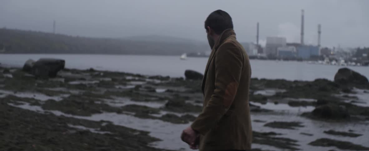 Man walking outside by the water on a cloudy day