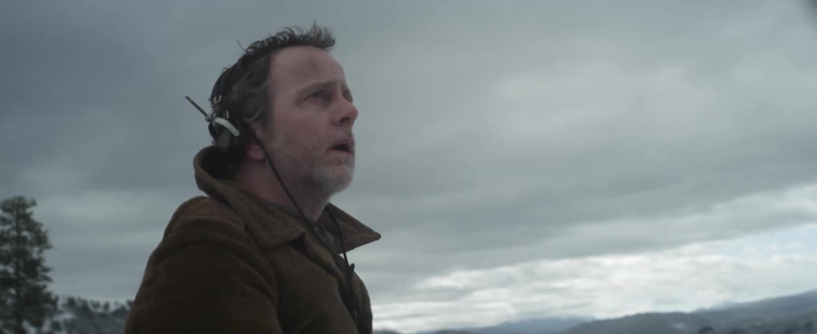 A man with headphones standing in a snowy field