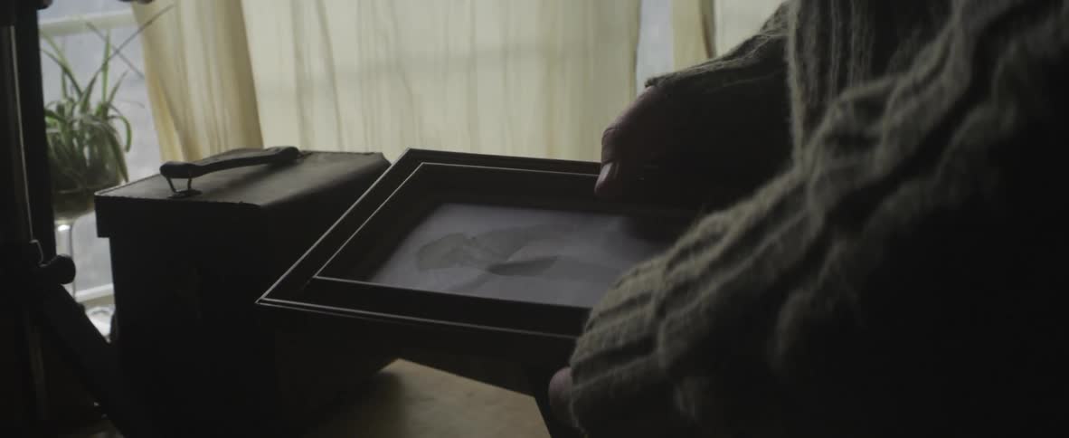 A framed photograph is picked up and examined