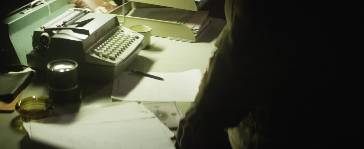 A man standing at a desk with papers and a typewriter