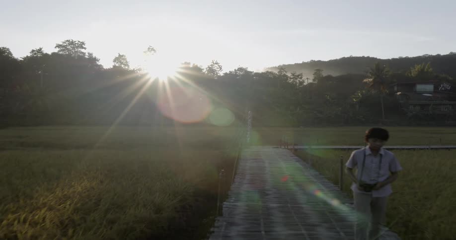 Man walks down a walkway under the bright sun